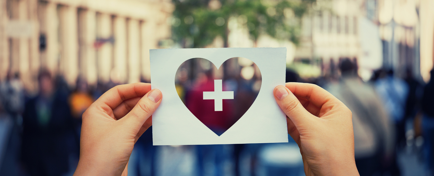 person holding a paper with a cutout heart and medical symbol